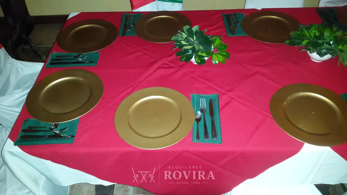 Mesa navideña con platos base dorados y camino de mesa rojo
