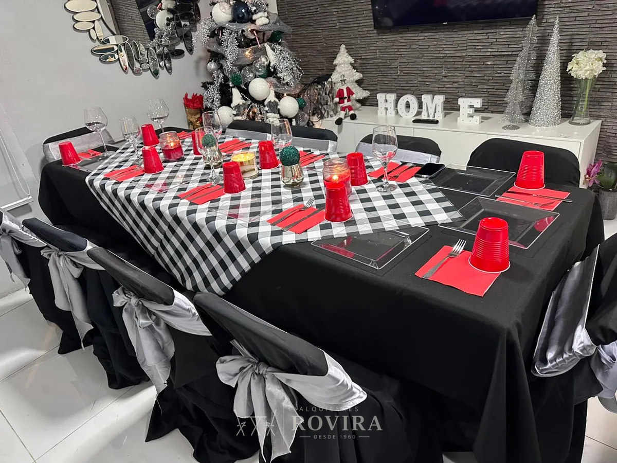Mesa negra con camino ajedrezado y servilletas rojas, montaje navideño