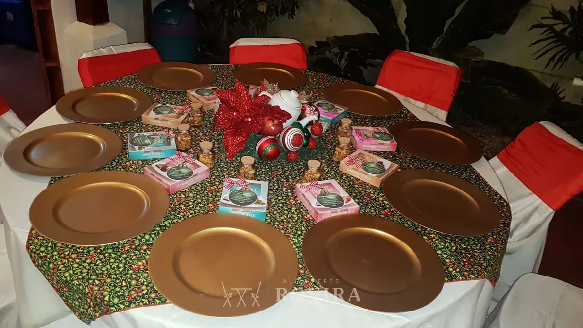 Puestos navideños con platos base dorados sobre mantel rojo