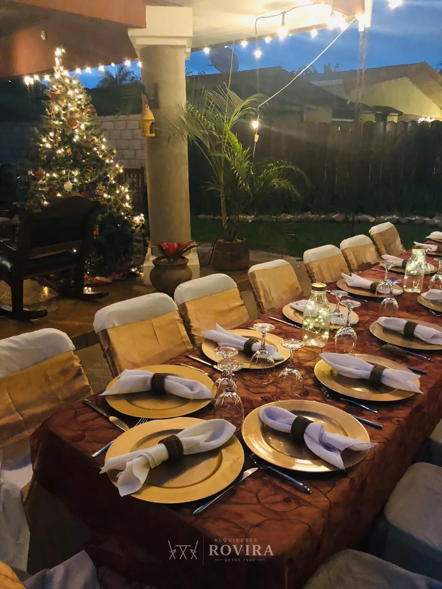 Mesa navideña elegante con platos base dorados y luces cálidas