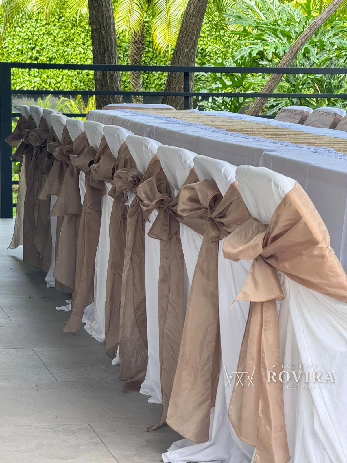 Detalle de cerca de lazos café en sillas forradas blancas, fila de sillas en terraza