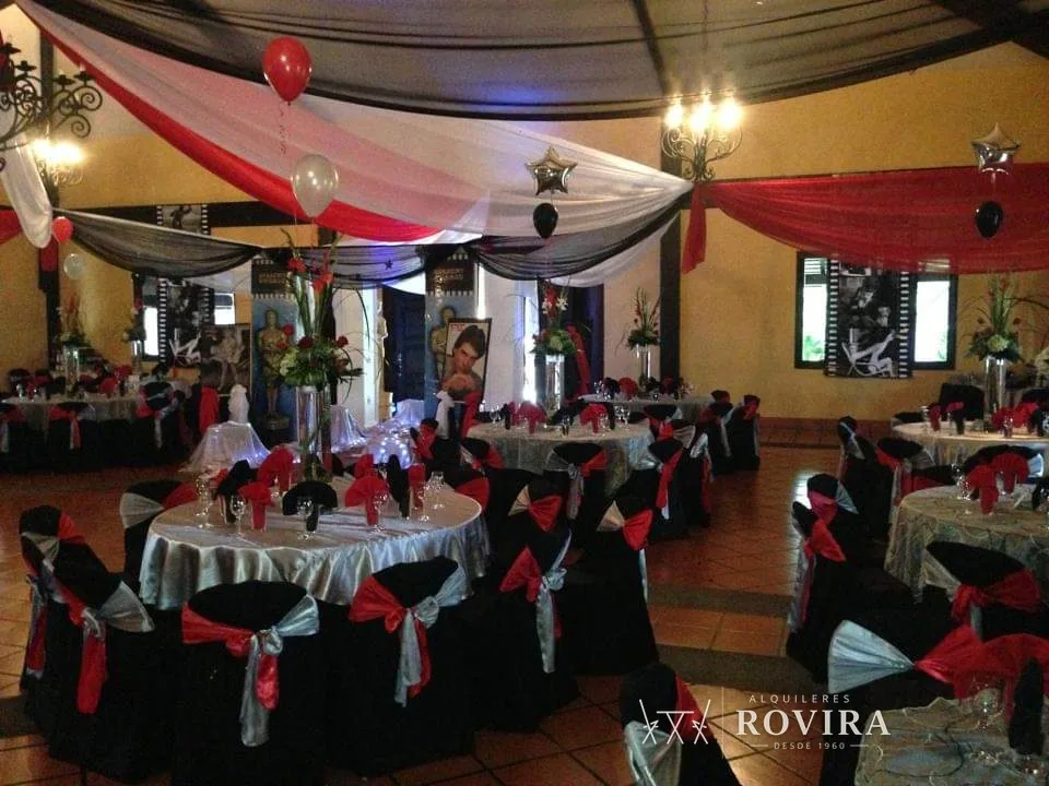 Salón temático en rojo, negro y plata con techo de tela y sillas negras con lazo rojo y plateado