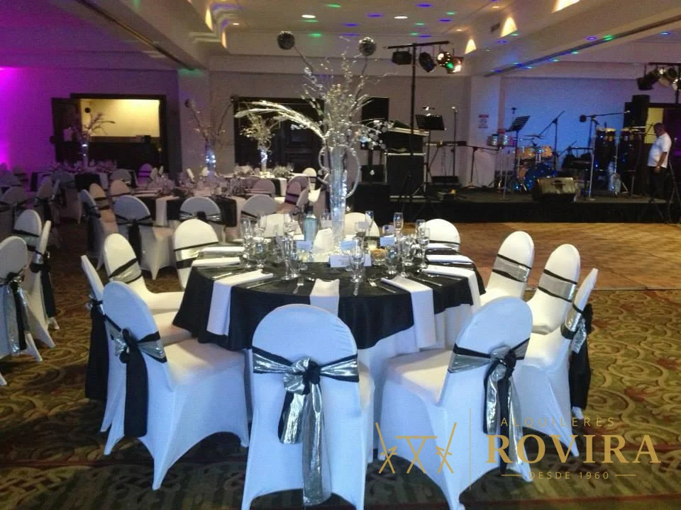 Salón de banquete con manteles negros, forros de silla blancos y lazos negros