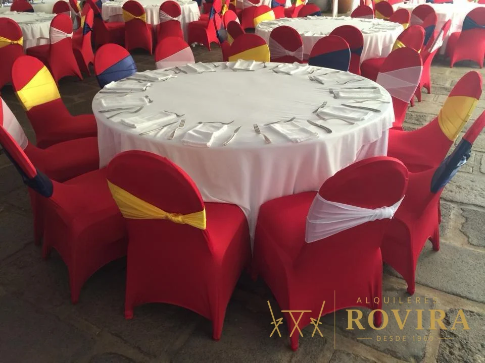 Mesa con forros de silla rojos y lazos amarillo y rojo sobre mantel blanco satinado