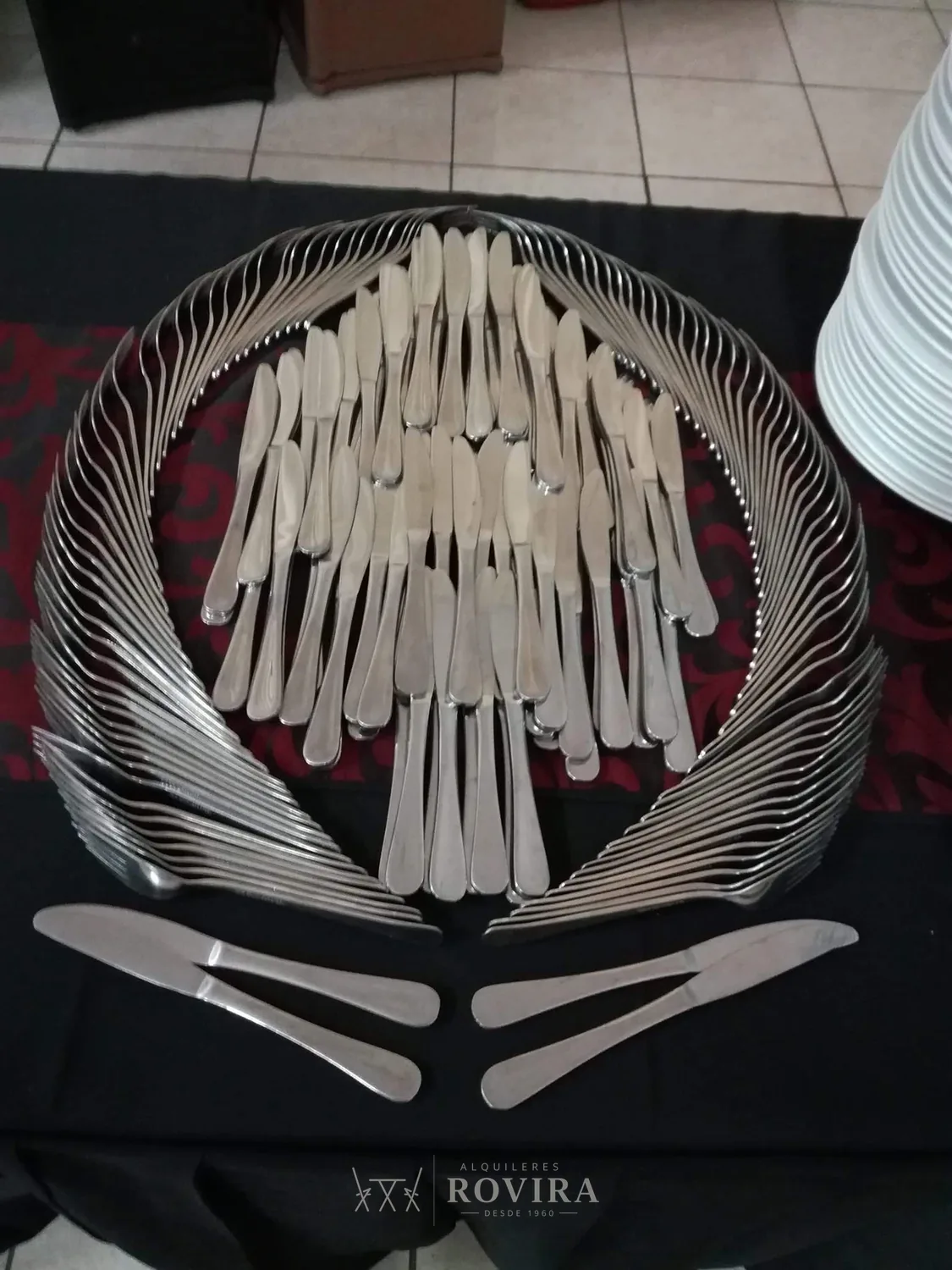 Cubiertos de acero dispuestos en abanico decorativo sobre la mesa