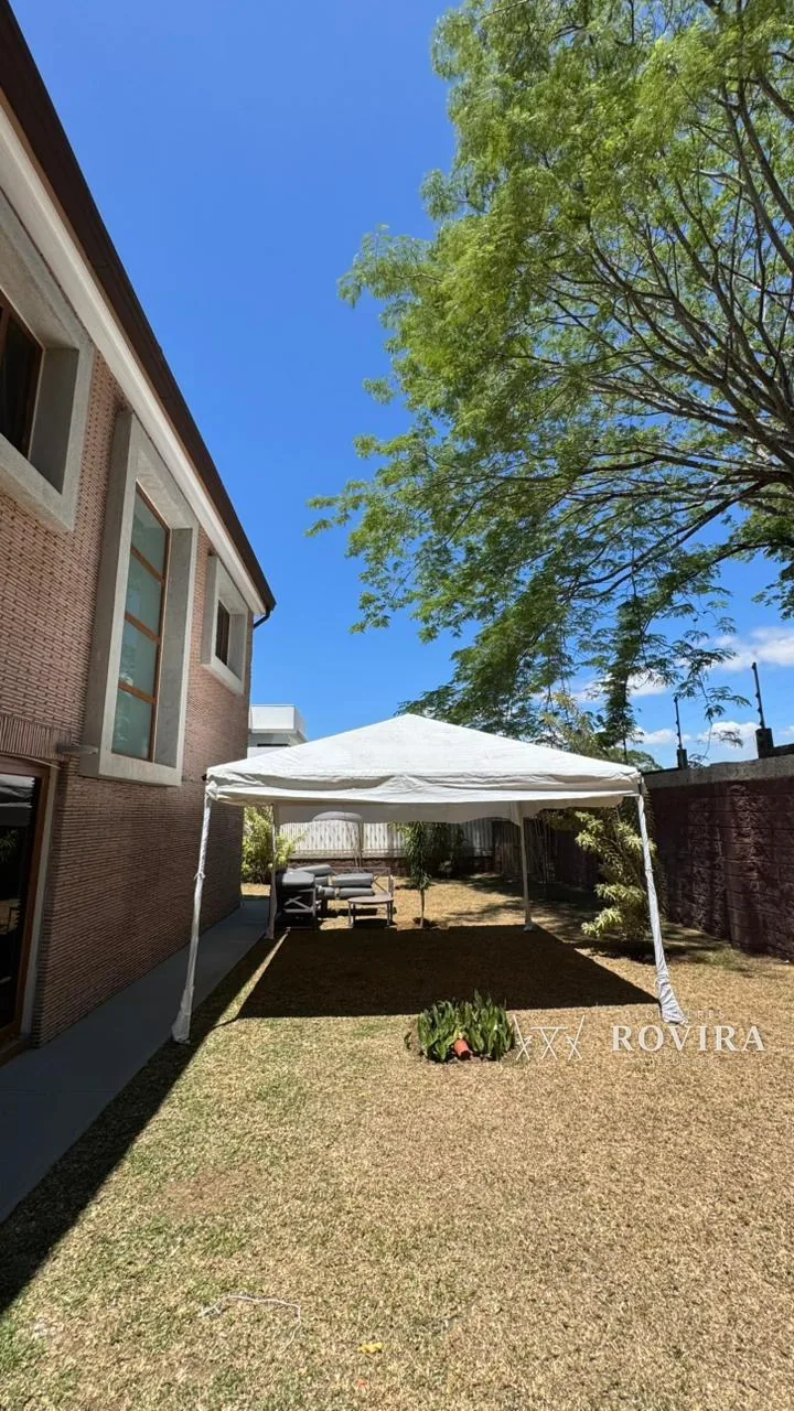 Toldo blanco en el patio trasero de una casa privada, jardín arbolado