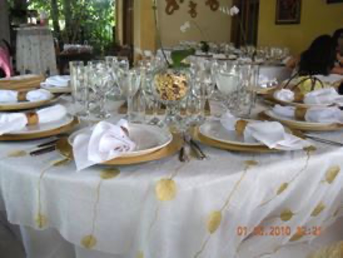 Mesa vestida en dorado con vajilla blanca, copas y servilletas doradas