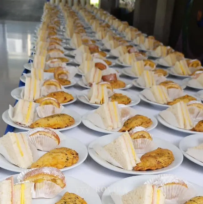 Postres y bocadillos en fila sobre mesa, montaje de buffet de catering