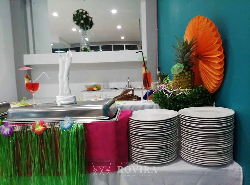 Buffet con decoración tropical y platos de servicio, catering de evento