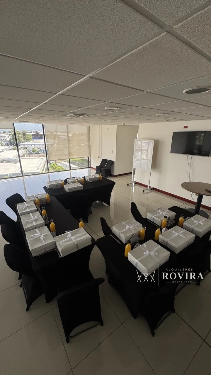 Mesas negras con cajas de regalo blancas y jugos individuales, sala corporativa con vista a la ciudad