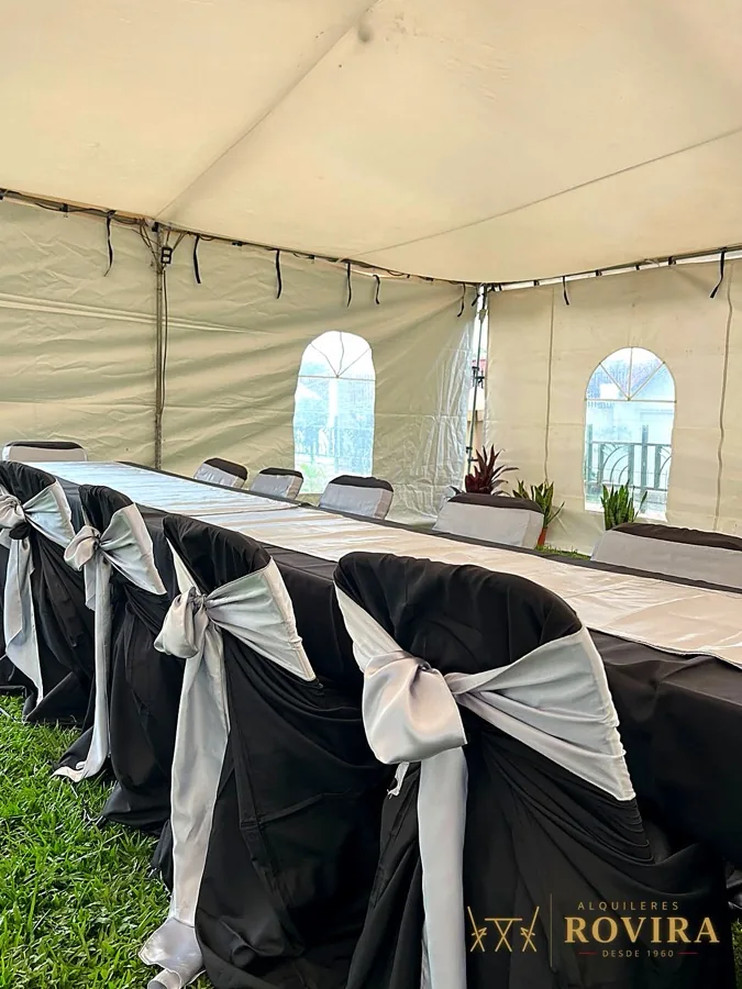 Interior de toldo blanco con ventanas arqueadas y sillas con lazos plateados