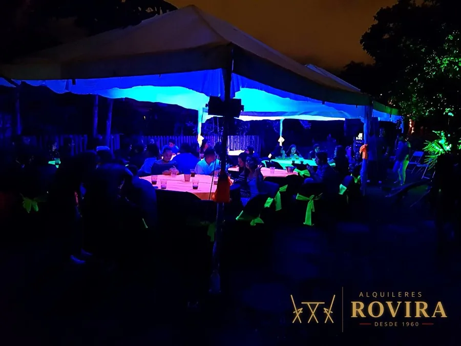Fiesta neón iluminada en azul bajo toldo, de noche