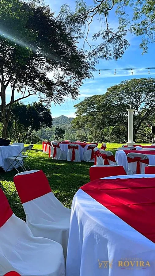 Jardín con mesas rojas y blancas, vista a la montaña